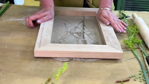 Pouring liquid plaster into wooden frame mold with floral imprints. DIY step of  Stock Footage 314187521