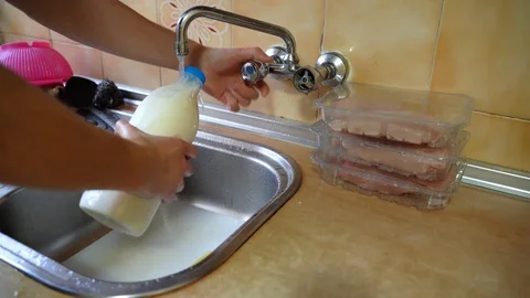 Pouring liquid soap on plastic milk bottle, disinfecting in kitchen sink Stock-Footage 127536403
