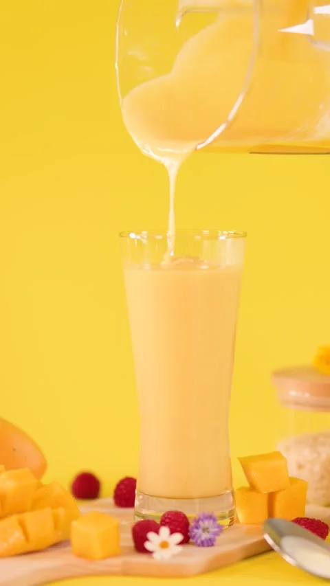 Pouring Mango Smoothie into Glass on Bright Yellow Background Stock Footage 323683098
