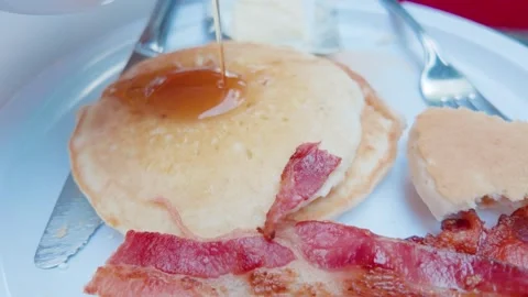 Pouring Maple Syrup on Pancakes with Crispy Bacon at Breakfast Stock Footage 345927465