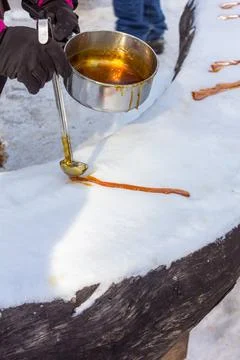 Pouring maple syrup on snow making maple taffy. Stock Photos