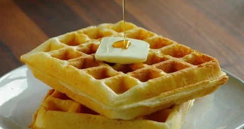Pouring maple syrup on top of a golden brown waffle Stock Footage 99735637