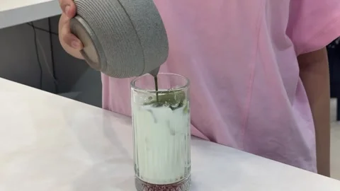 Pouring matcha into iced milk, vertical close-up Stock Footage 345160033