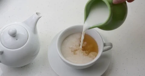 Pouring milk into black ceylon tea teapot cup  at 200FPS Stock Footage 126722754