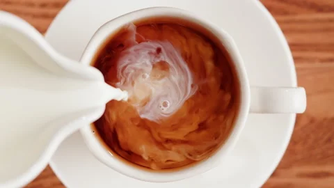 Pouring milk into black tea top view. Freshly brewed green tea ceremony process Stock Footage 190886193