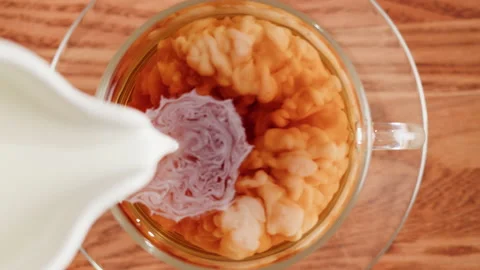 Pouring milk into black tea top view. Freshly brewed green tea ceremony process Stock Footage 190888882