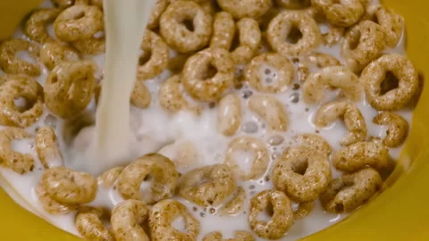 Pouring milk into bowl of ring flakes. Healthy breakfast of cheerios with milk. Stock Footage 146628482