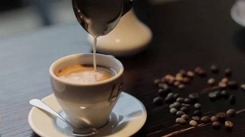 Pouring milk into coffee in cafe Stock Footage 68925625