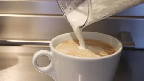 Pouring milk in coffee cup making cappuccino Stock Footage 131075592