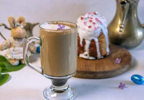 Pouring milk into coffee with Easter cake and plush bunny on background. 库存照片