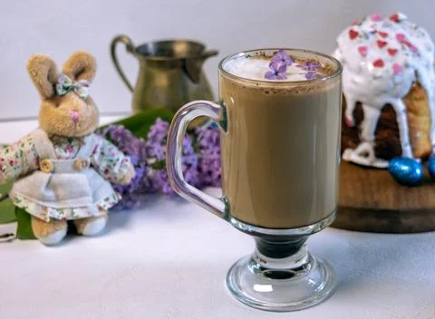 Pouring milk into coffee with Easter cake and plush bunny on background. 库存照片