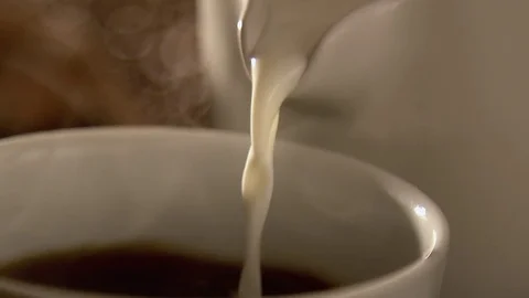 Pouring milk in coffee in slow motion Stock Footage