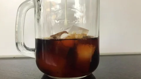 Pouring milk into cold brew coffee, slow motion. authentic kitchen scene Stock Footage 127117616