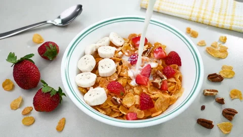 Pouring milk in cornflakes cereal Stockbeeldmateriaal 229828390
