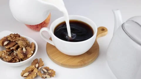 Pouring milk into a cup of coffee Stock Footage 155138737