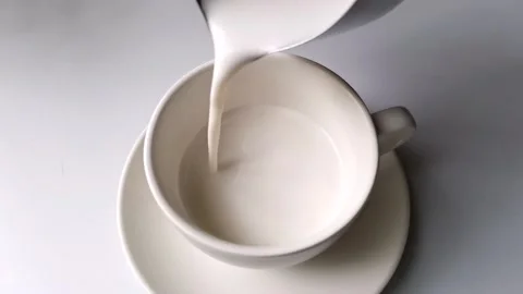 Pouring milk into a cup of coffee Video stock 208843577