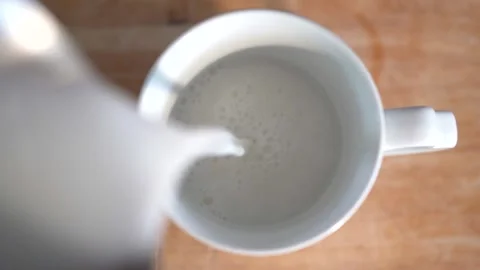 Pouring milk in cup, top down view Stock Footage 131048904