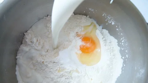 Pouring milk into flour. Stockbeeldmateriaal 86359579
