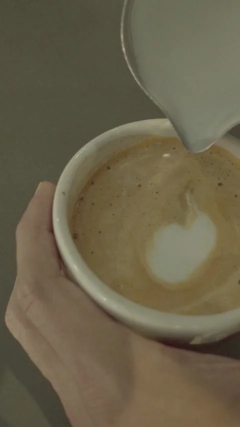 Pouring Milk Foam into Coffee Cup to Create Latte Art Heart Stock Footage 334697803