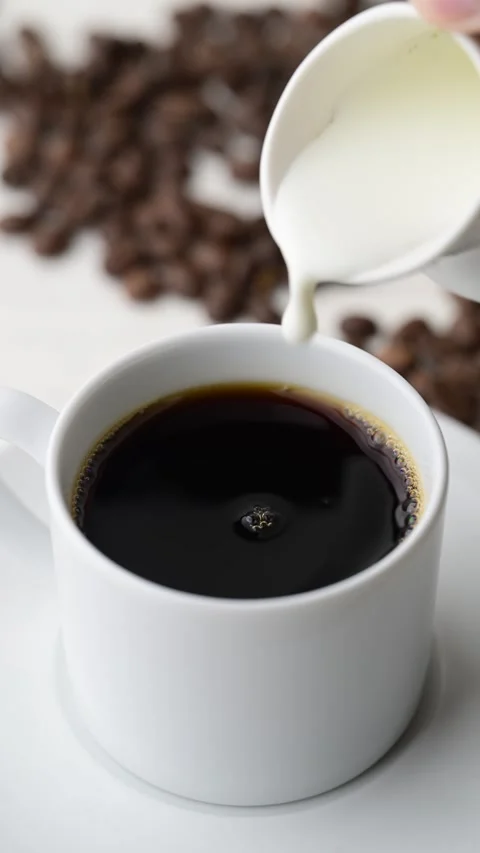 Pouring milk into hot coffee Stock Footage 273638381