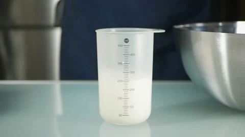 Pouring milk into measuring cup at kitchen Stock Footage 169278674