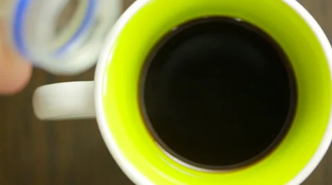 Pouring milk into a mug of coffee. view from above Stock Footage