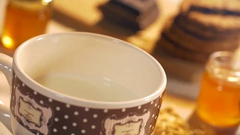 Pouring milk into a mug during the breakfast in a warm morning. Stock Footage 69852176