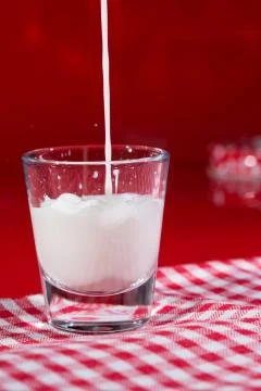 Pouring milk on red background Stock Photos