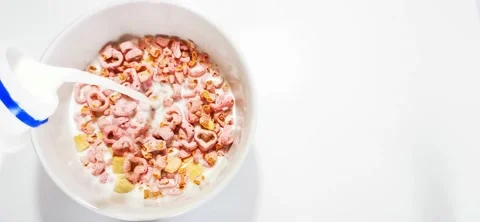 Pouring milk into a white cup, containing Fiber cereal Strawberry Shotcake. Stock Footage 158519225