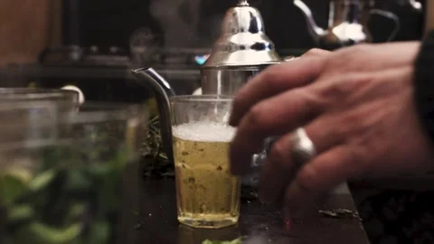 Pouring mint tea in a glass from a height to make foam Stock Footage 243572782