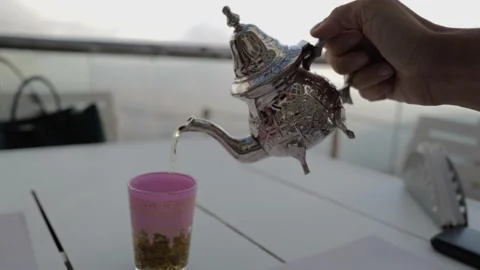 Pouring Moroccan mint tea from the silver pot at the cafe above the clouds 스톡 동영상 164864021