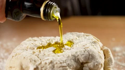 Pouring oil from a bottle over bread dough in slow motion 4K close-up Stock Footage 266216822