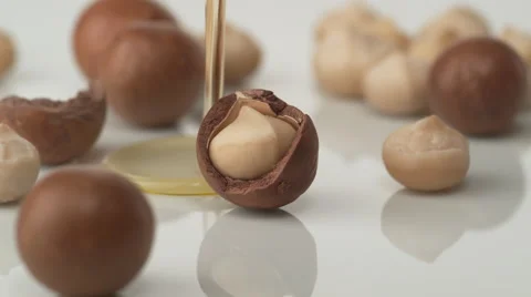 Pouring oil on macadamia nuts. Slow Motion. Stock Footage