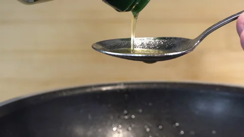 Pouring olive oil into a tablespoon while cooking a meal Stock Footage 224564324