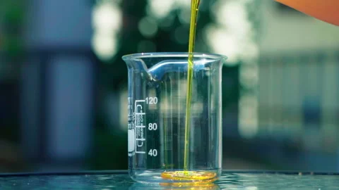 Pouring orange emulsion to beaker bokeh background slowmotion 100fps Video stock 156154530