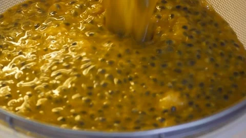 Pouring passion fruit pulp into a sieve for processing. Stock Footage 252915936