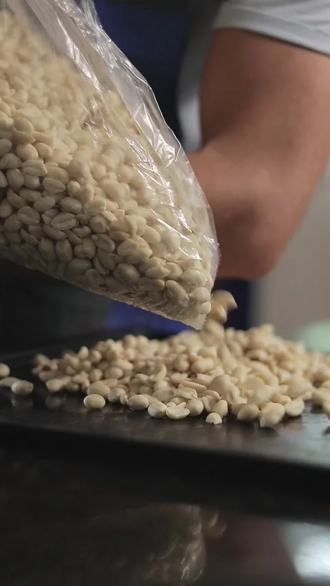 Pouring peeled peanuts from a plastic bag onto a tray Stock Footage 305855684