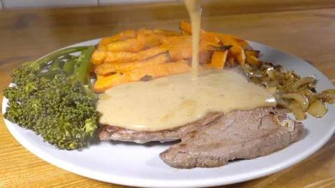 Pouring pepper sauce on a steak dinner. Stock Footage 129170351