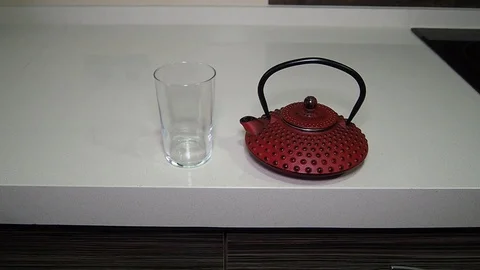 Pouring red herbal tea from amazing red teapot in glass Stock Footage