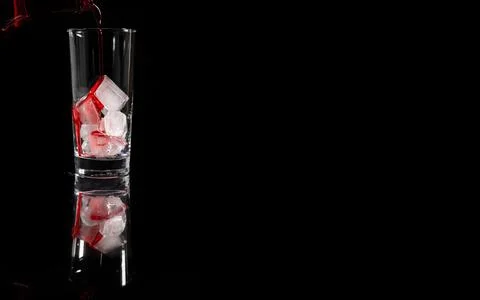 Pouring red non alcoholic solution on the top of the ice into the glass again Stock Photos