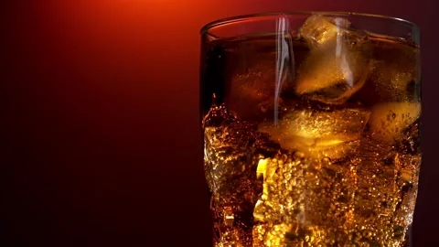 Pouring red soft drink into a glass against red background. Slow motion Stock Footage 194767592