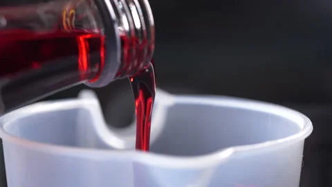 Pouring red syrup into a cup Stock Footage 134987116