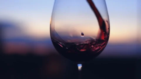 Pouring red wine into a glass at sunset Stock Footage