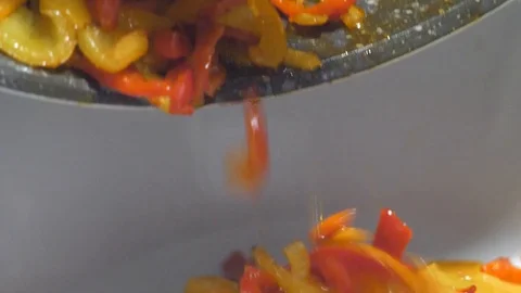 Pouring red yellow peppers on the serving dish Stock Footage 117617818