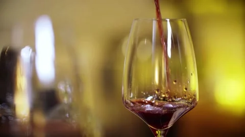 Pouring a rich and vibrant Red Wine into a beautifully crafted Glass enhances Stock Footage 294603368