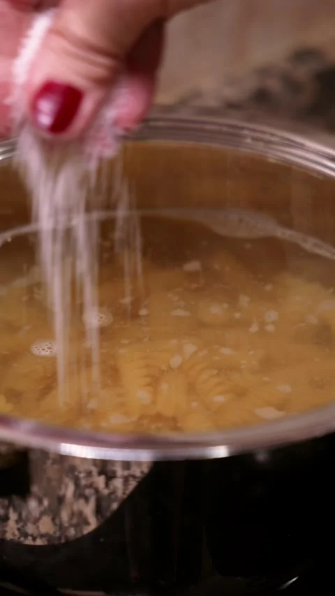 Pouring salt in boiling pasta. 動画素材 346620430