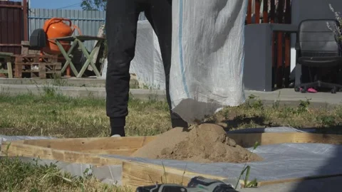 Pouring sand into a sandbox in the backyard Stock Footage 314309066