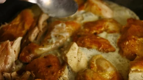 Pouring sauce with a spoon over carved big oven roasted chicken stewing in Stock Footage 151431053