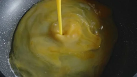 Pouring the scrambled eggs into a hot pan and putting champignons on eggs Video stock 166327306