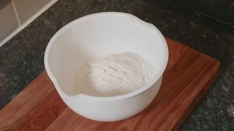 Pouring several cups of flour into a large mixing bowl Stock Footage 119185363